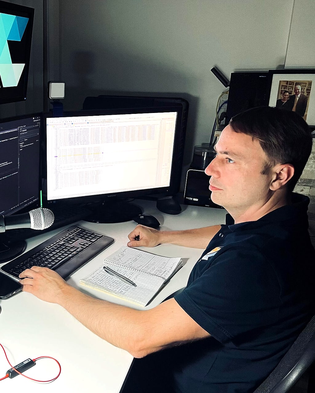 Nikita Gurov at his desk writing code in Visual Studio, with an engineering data grid open on the second monitor
